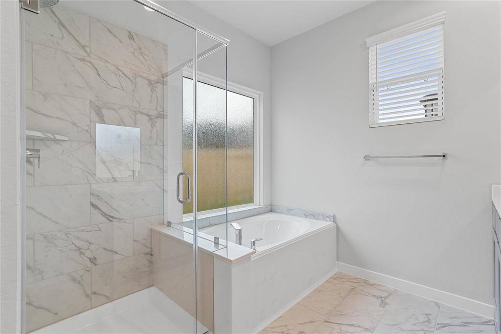 Additional view of the primary bathroom featuring the large garden tub and walk-in shower with tile surround.