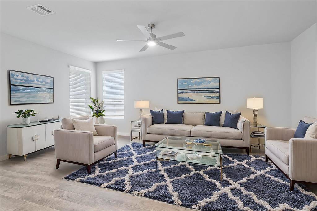 This family room is a perfect room! Featuring custom paint, wood look tile flooring, high ceilings with ceiling fan, and windows with privacy blinds providing natural light into this beautiful room.