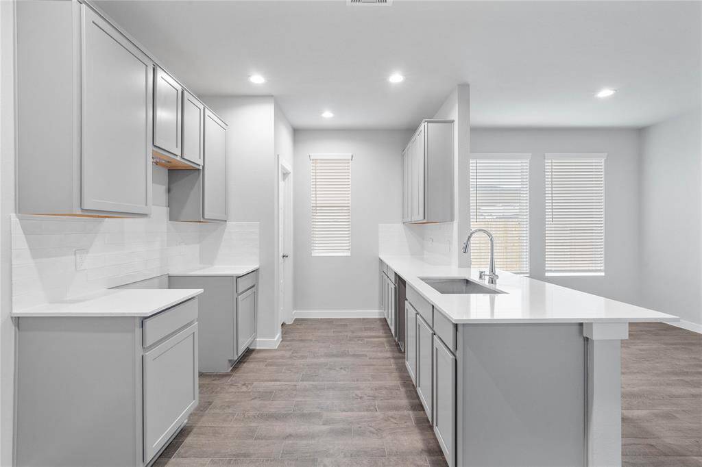 Any chef's dream, this stunning kitchen is perfect for everyday life as well as entertaining family and friends! This kitchen features stained cabinets, quartz countertops, windows with privacy blinds, high ceilings with recessed lighting, and a pantry!