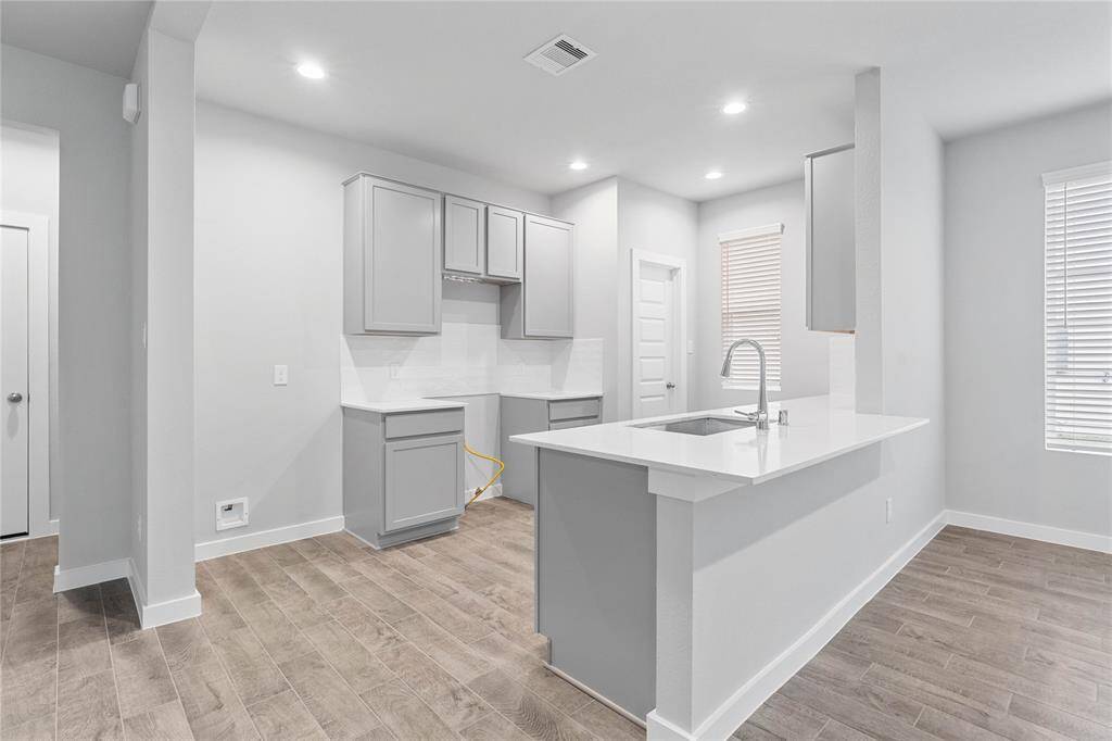 Another gorgeous view of this spacious kitchen featuring the wood look tile flooring and the extended countertop for a breakfast bar!
