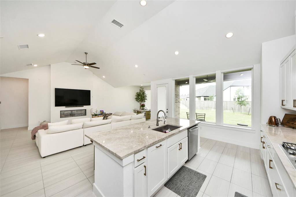 This expansive open-concept living area features high vaulted ceilings, a modern fireplace, and large windows that flood the space with natural light—perfect for relaxing or entertaining.