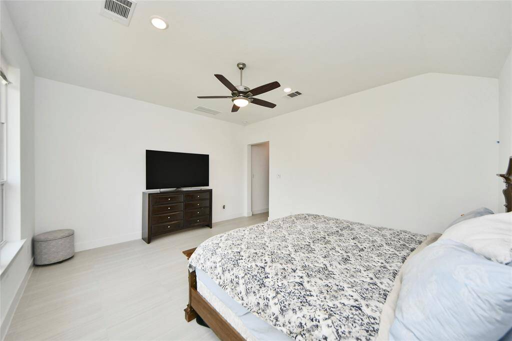 Second angle of the spacious primary bedroom, featuring tile flooring and a ceiling fan for added comfort.