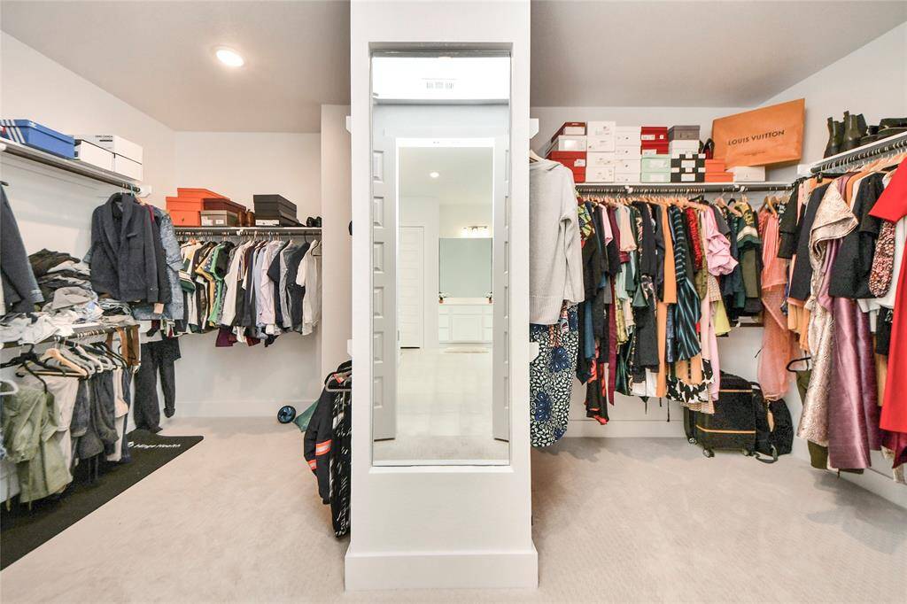 Expansive walk-in closet with built-in shelving, double hanging space, and a full-length mirror—fashion lover’s dream!