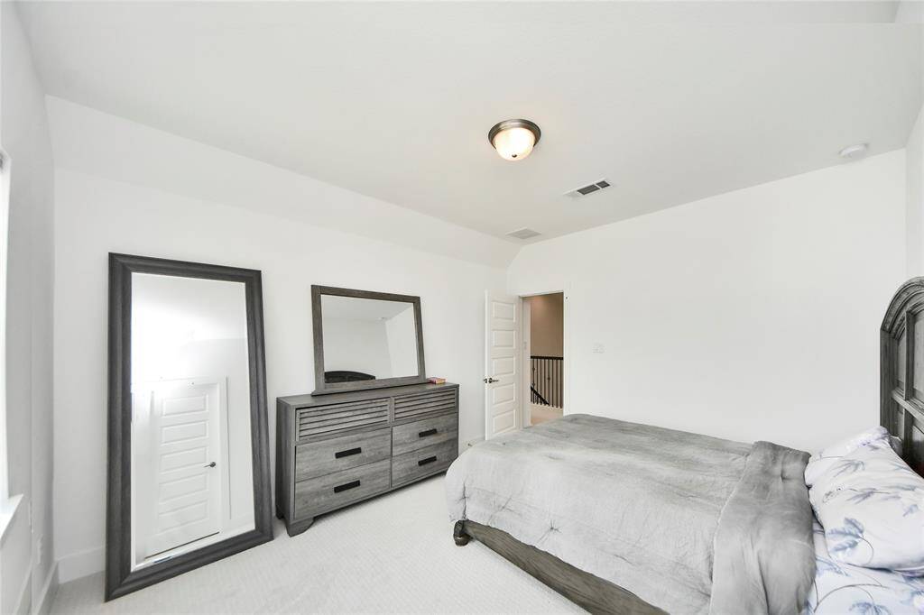 Another angle of the upstairs bedroom reveals its spacious layout and large dresser, along with access to the hallway and additional storage.