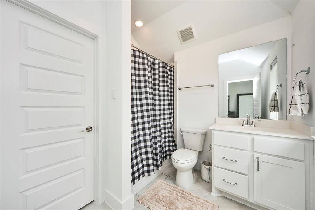 This full bathroom offers clean lines with a modern white vanity, a large mirror, and a tub/shower combo with stylish tile.