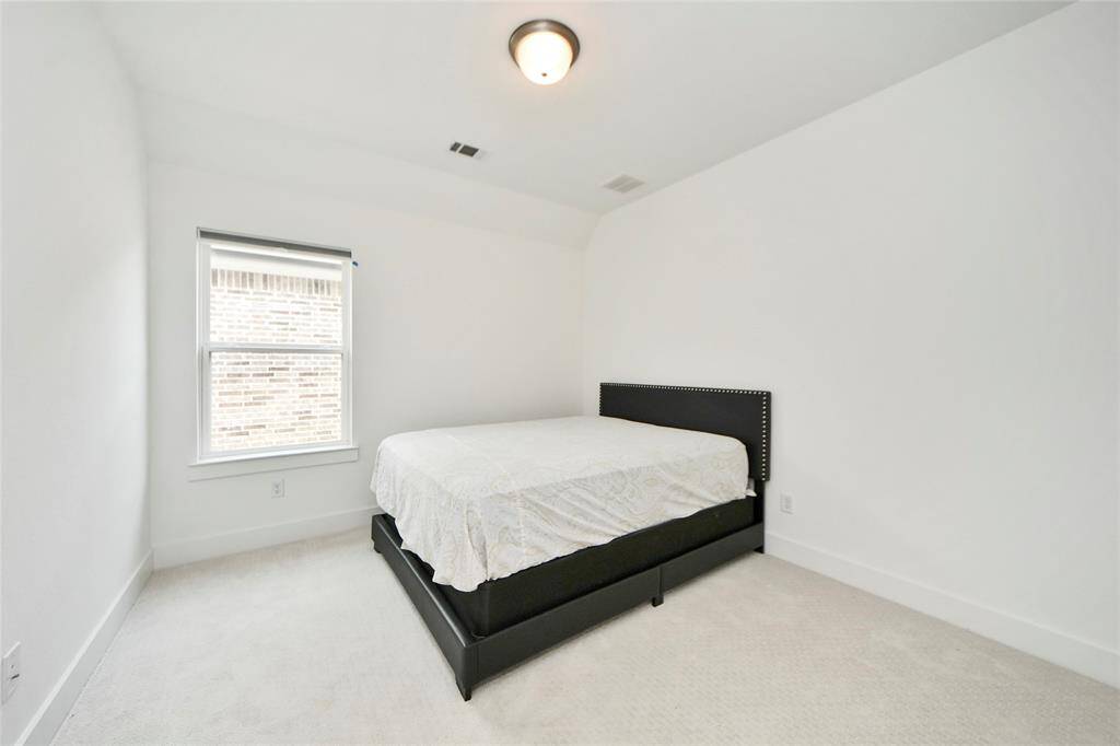 A simple yet spacious upstairs bedroom with light carpeting, a window for natural light, and room for a queen bed setup.