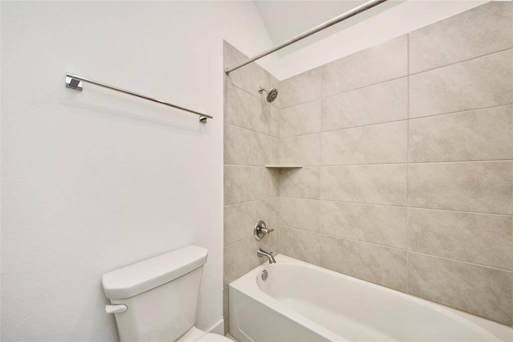Close-up of the modern tiled shower and tub combo with neutral tones—ideal for both guests and family.