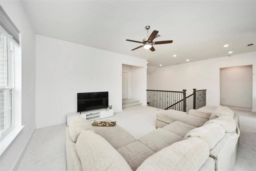 Expansive upstairs game room with natural light and ceiling fan, ideal for entertaining or relaxing.