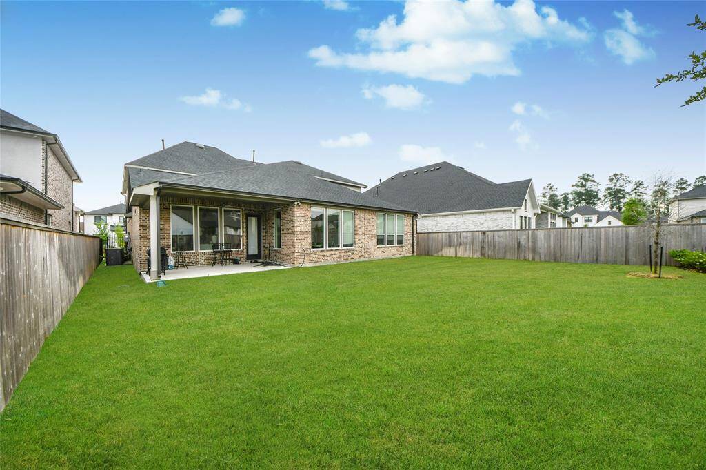 Inviting covered patio ideal for entertaining, paired with a wide lawn that offers flexibility for outdoor living or customization.