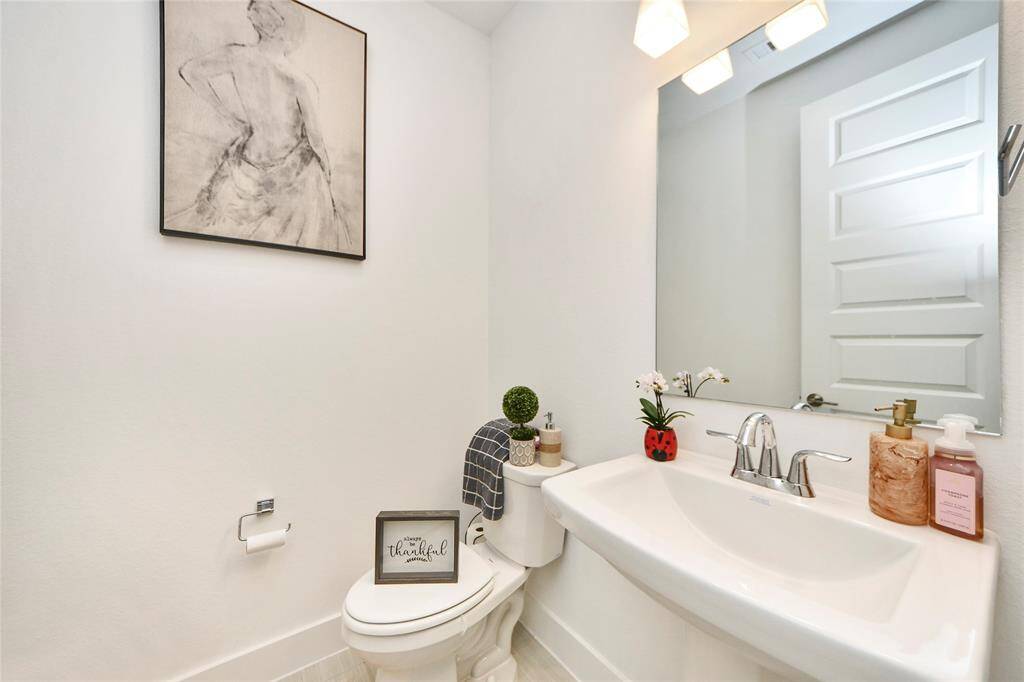 Stylish half bath with a pedestal sink, framed mirror, and modern lighting—perfectly appointed for guests.