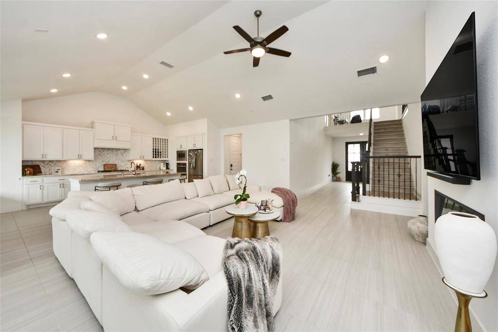 Wide-angle view of the main living space showcasing the flow into the gourmet kitchen and upstairs overlook.