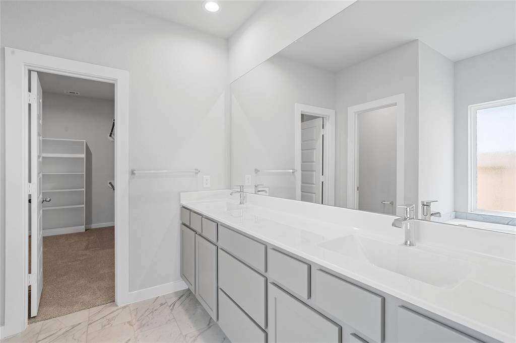 This primary bathroom is definitely move-in ready! Featuring stained cabinets with light countertops and dual sinks, spacious walk-in closet with shelving, high ceilings, custom paint, sleek fixtures, and dark modern finishes.