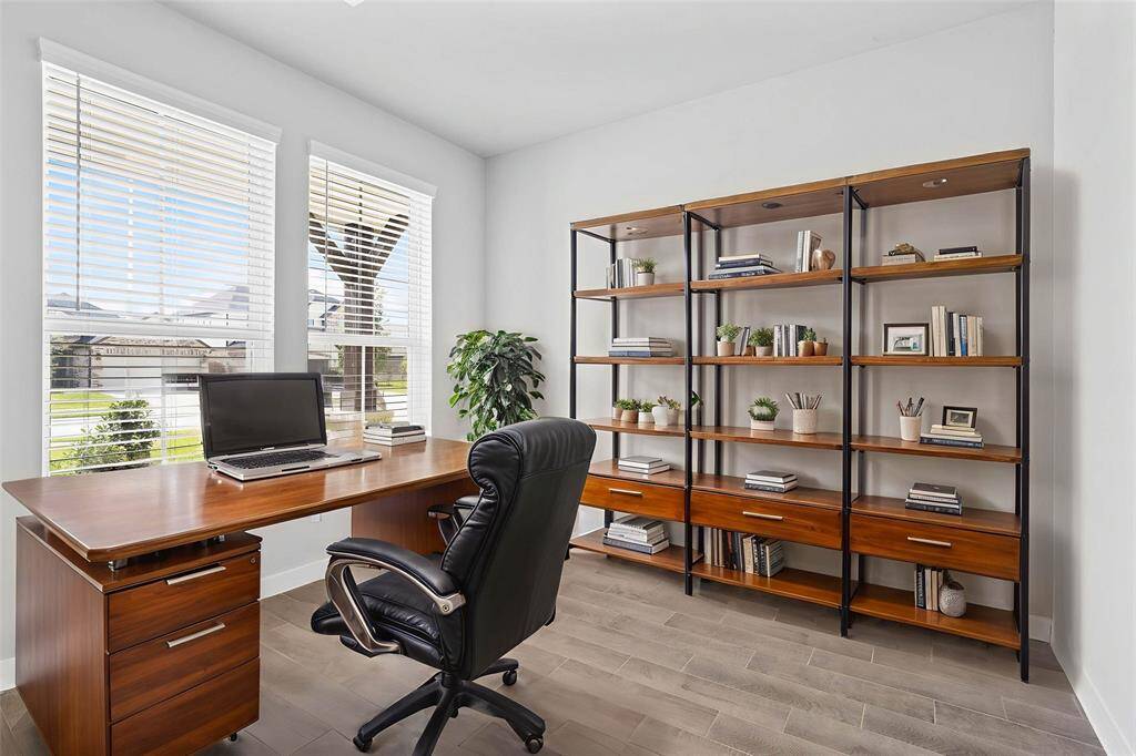 Quietly nestled in front of the home is the handsome home office. Featuring wood look tile flooring, high ceilings, large windows with privacy blinds and custom paint.