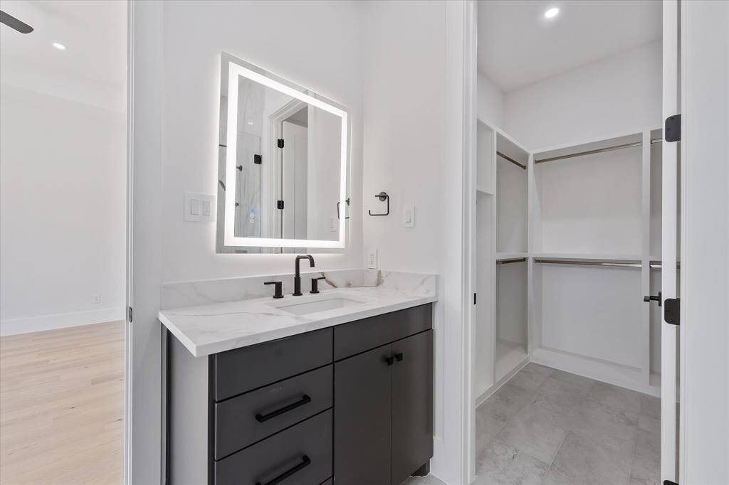 Primary Bathroom: Custom built vanity with LED lit mirror and view of the Primary walk-in Closet.