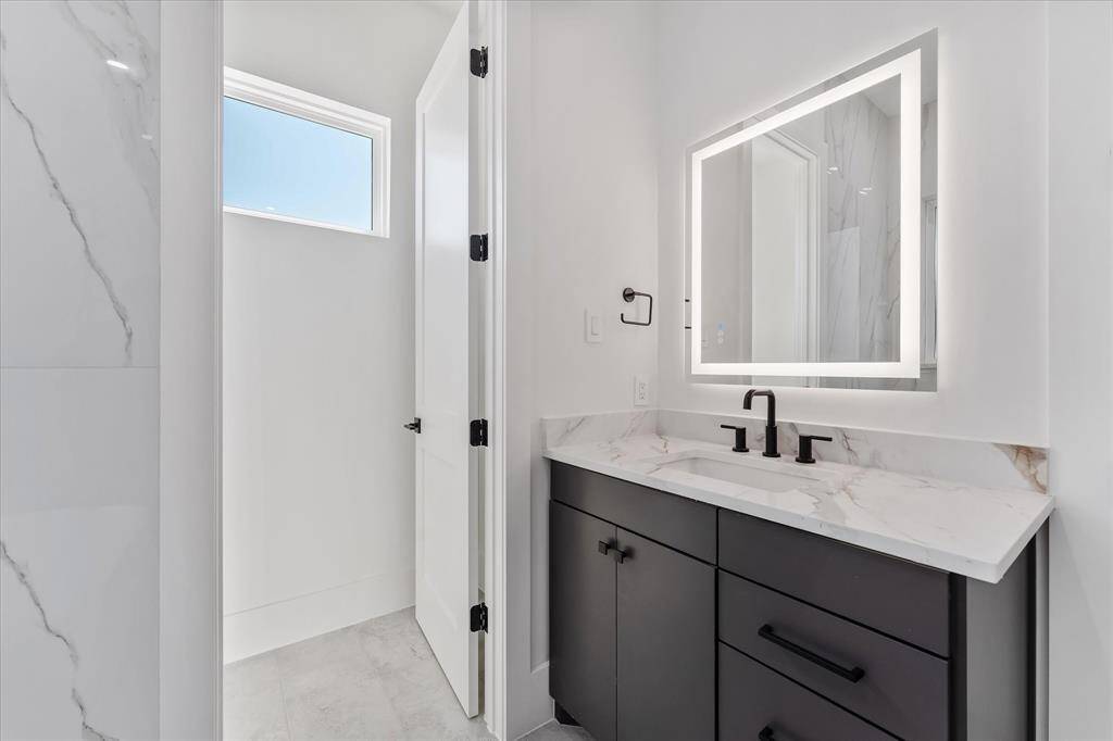 Primary Bathroom: Custom built vanity with LED lit mirror. Door to the left, is to the water closet.