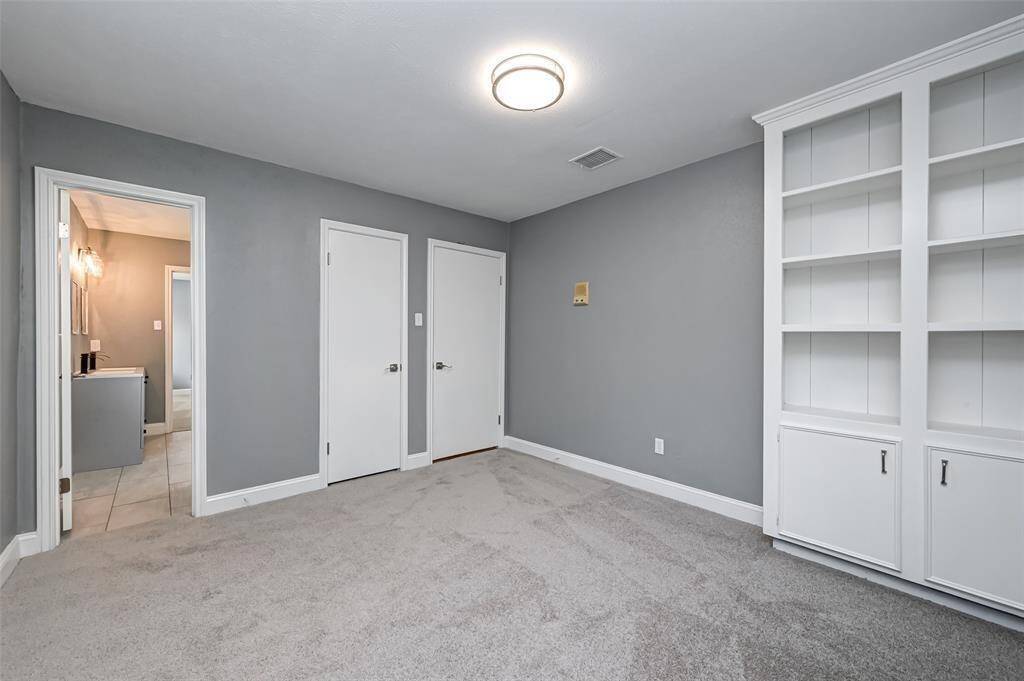 Secondary bedroom features built-in shelving and plush carpet.