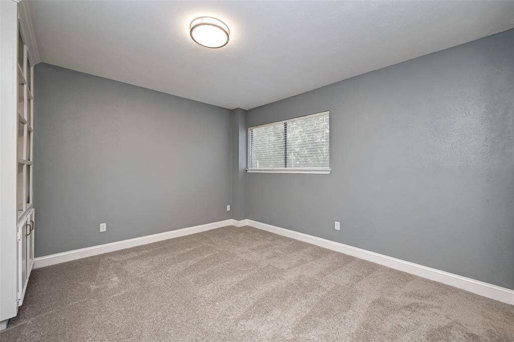 Secondary bedroom features built-in shelving and plush carpet.