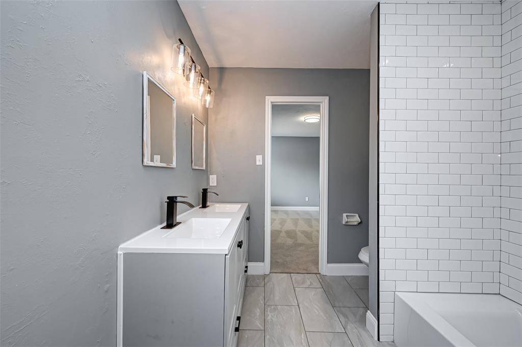 Secondary bathroom features dual sinks, tile floors, and custom paint.