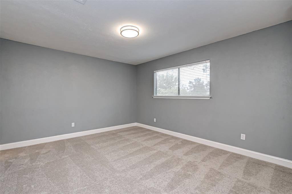 Fourth bedroom features awindow and plush carpet.