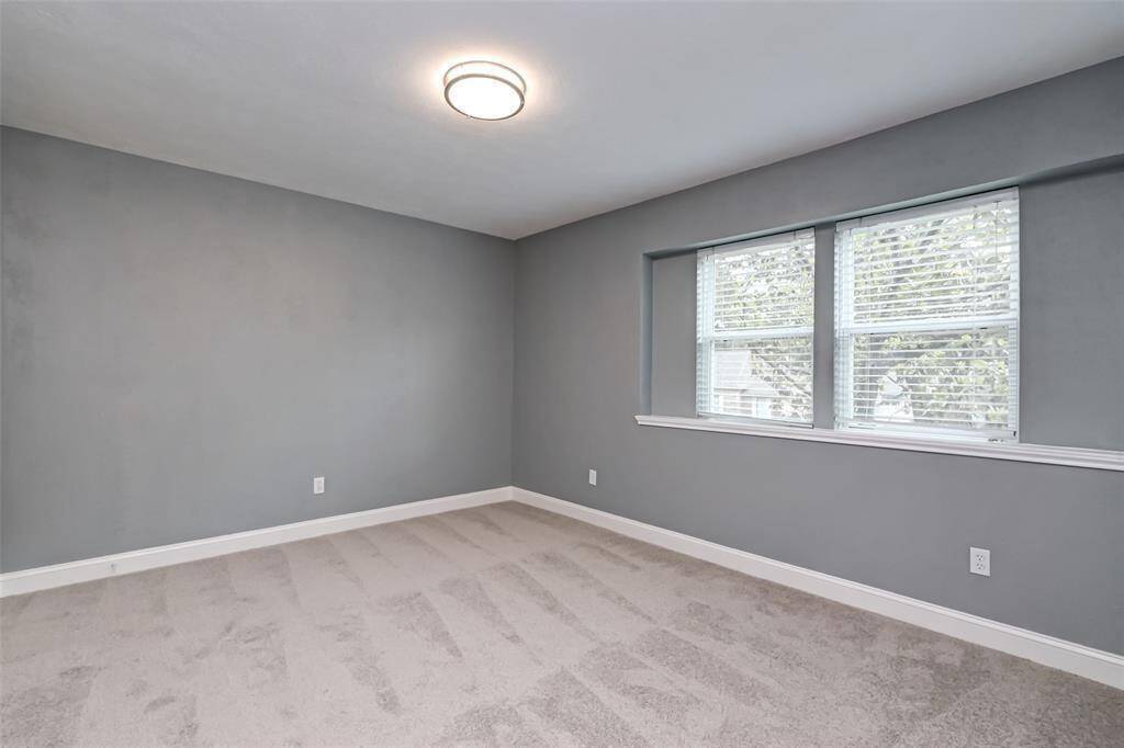 Fifth bedroom features awindow and plush carpet.