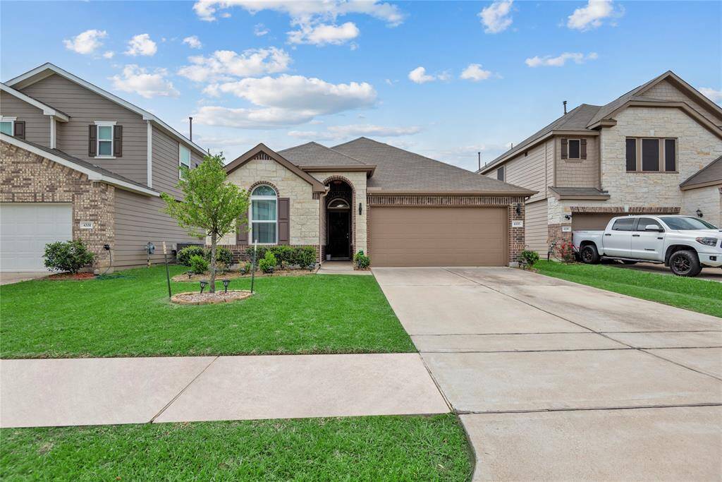 Charming single-story home with a two-car garage and well-maintained front yard. Features a brick and stone facade, a neat driveway, and a welcoming entryway.