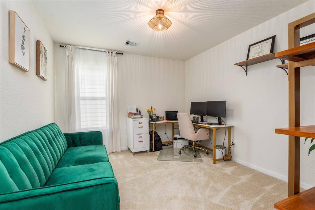 This photo shows the flex room. It can easily be used as an additional room, game room, etc. Now used as a bright home office with a cozy atmosphere. The room is carpeted, with a modern light fixture and a window that lets in natural light, creating an inviting workspace.