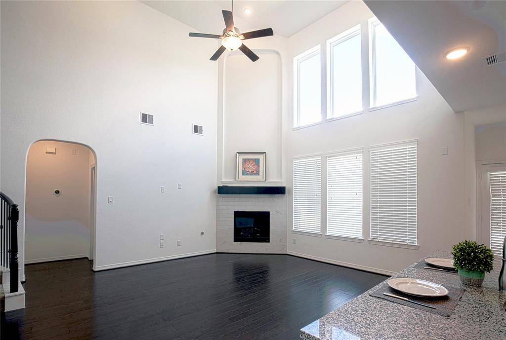 Den with high ceiling, lots of window, fireplace, and hardwood floor.