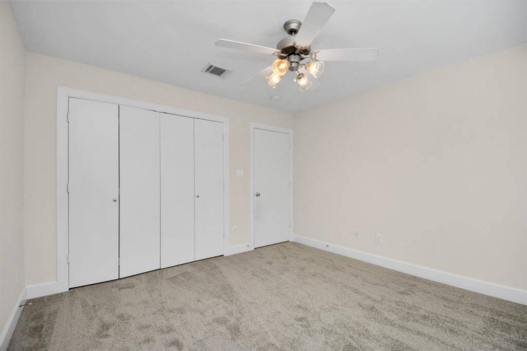 The downstairs bedroom with a ceiling fan and extra large closet.