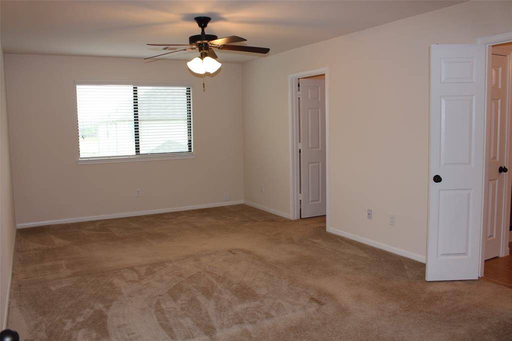 Spacious primary bedroom with ample natural light and a ceiling fan for comfort.