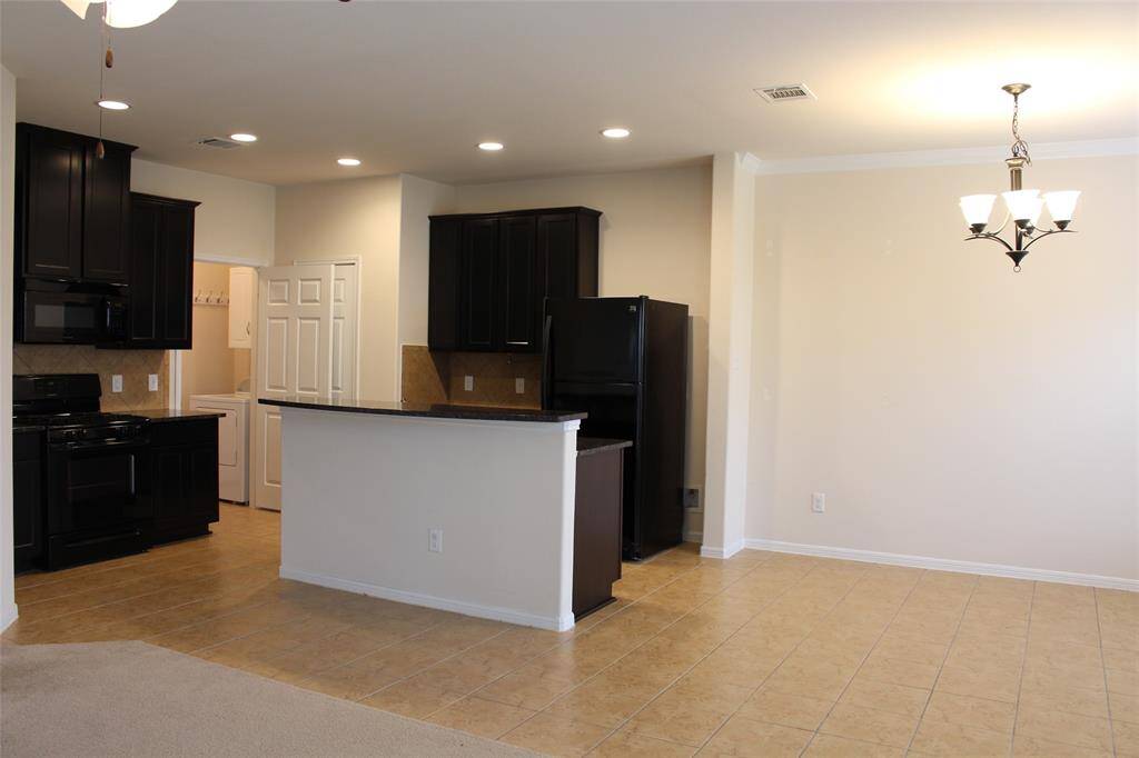 The kitchen boasts dark cabinetry, black appliances, and a breakfast bar.