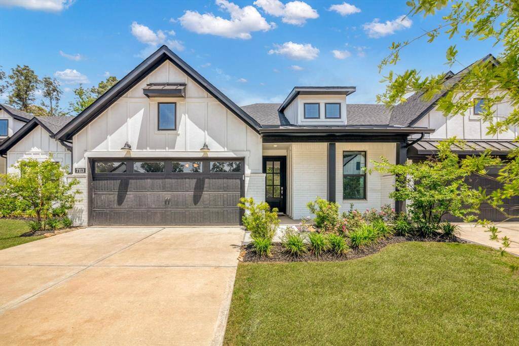 This modern home features a sleek black and white exterior with a gabled roof and large windows. It has a spacious driveway, a two-car garage, and well-maintained landscaping, offering great curb appeal.
