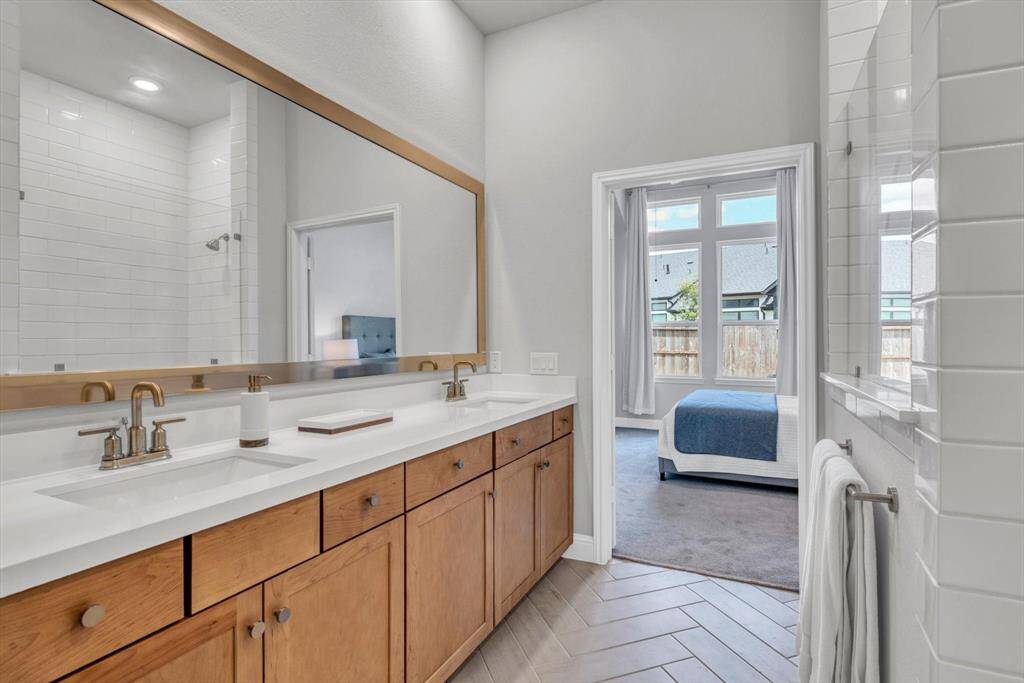 Primary bathroom featuring a double vanity with wooden cabinets and sleek fixtures.