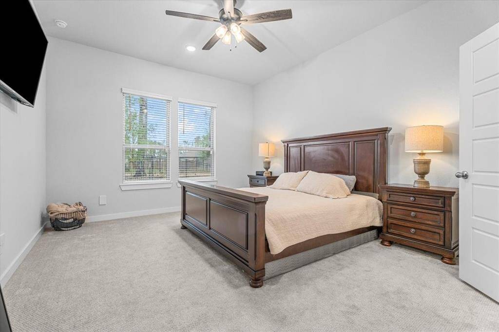 The primary features neutral walls and carpet, a large window for natural light, and a ceiling fan. This primary suite is a sophisticated retreat.