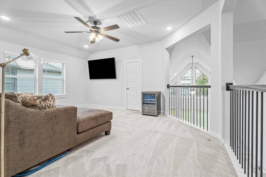 Bright, modern loft space featuring a ceiling fan, flat-screen TV which will be excluded but bracket system will stay. Large windows and open railing provide ample natural light and a spacious feel.