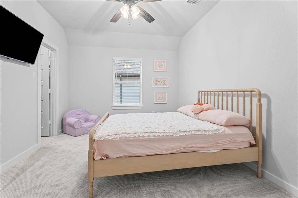 This is a one of three upstairs bedroom, featuring carpet, ceiling fan, and wall-mounted TV. TV will be excluded but wall mount will stay. There is an ensuite bathroom and a large walk-in closet.
