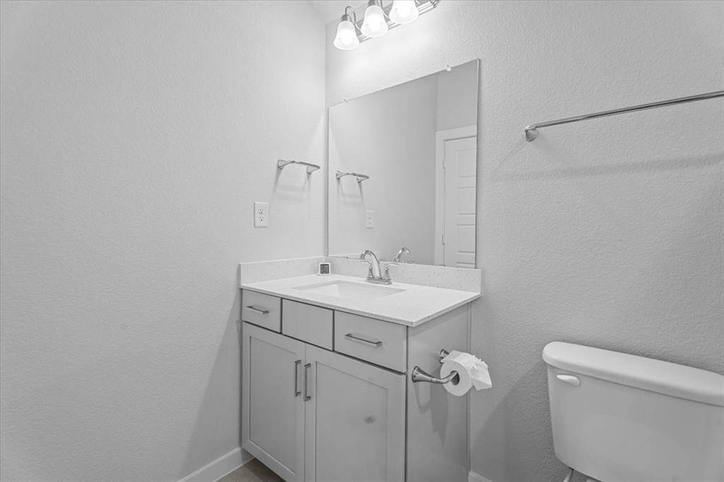 The ensuite bathroom with a vanity and overhead lighting. Neutral tones create a clean and bright atmosphere. The shower features a tub-shower combo with modern tile and sleek finishes.