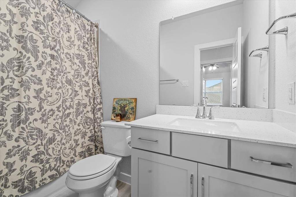 This second upstairs bathroom features a modern design with a light color palette, a spacious vanity with ample storage, and a large mirror. The shower features a tub/shower comb, again with beautiful tile, adding a touch of elegance.
