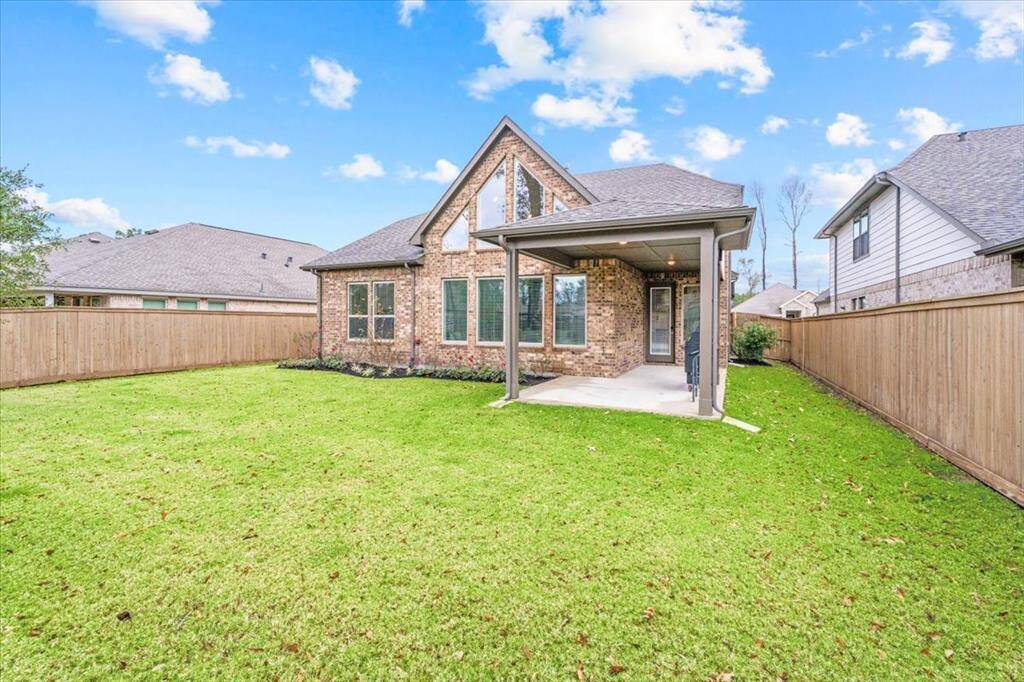 This backyard showcases a charming yard, lots of room for entertaining. The home features a covered patio area. The roof has an attractive gable design, and the property is surrounded by neighboring houses, offering a cozy community feel.