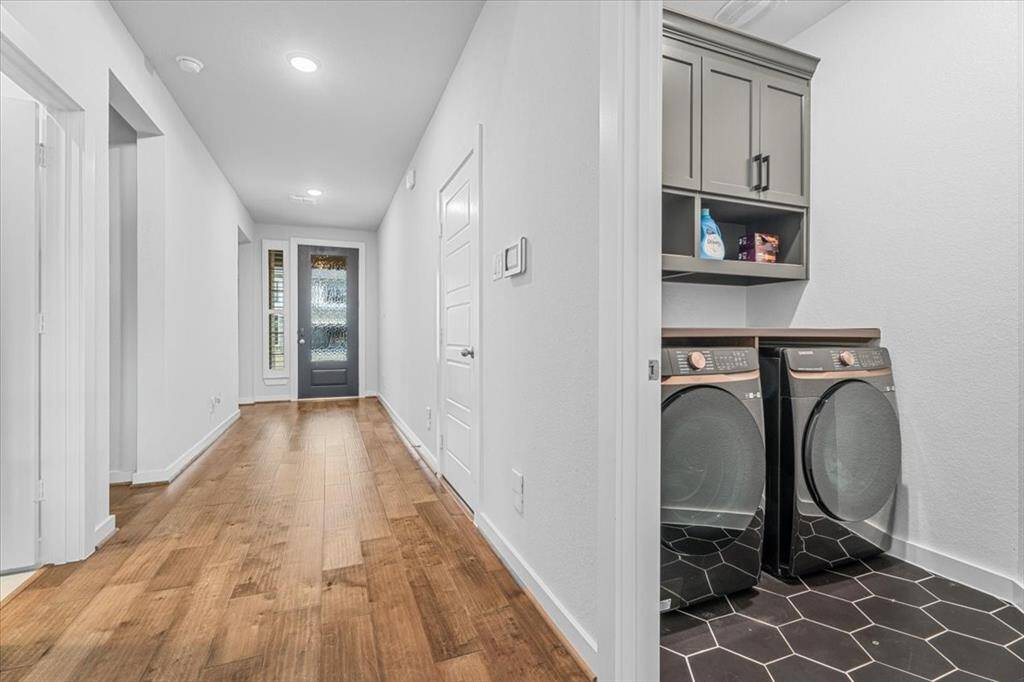 This residence features a large walk-in utility room with custom cabinets, modern flooring finishes and lots of storage.