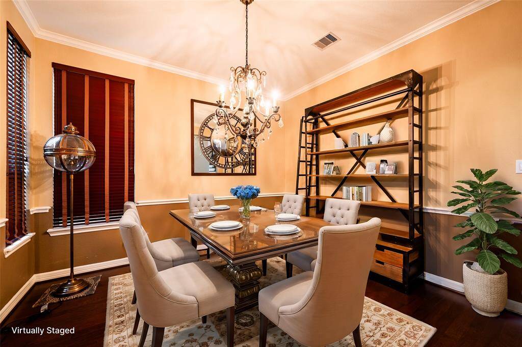 The dining/living space seamlessly combines functionality and style, showcasing rich hardwood floors and warm, neutral walls with wainscoting accents. The Restoration Hardware Victorian brass standing lamp exudes vintage nautical charm, while the Dutch Shipyard Bookshelf with its ladder serves as a unique focal point, offering ample storage. Both are available for sale. A striking wall mirror enhances the room's character, and a classic chandelier adds a touch of sophistication to the inviting ambiance.