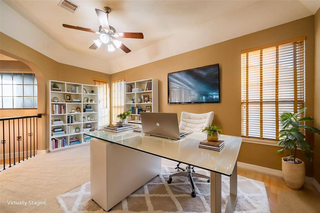 This versatile family/game room offers an open and inviting space with soft carpeting, tray ceilings, and large windows for natural light. The room's layout provides easy access to adjacent spaces, including the private home theater. Wrought iron railings and arched entryways add elegance, making it perfect for relaxation, gaming, or entertaining. Virtually Staged
