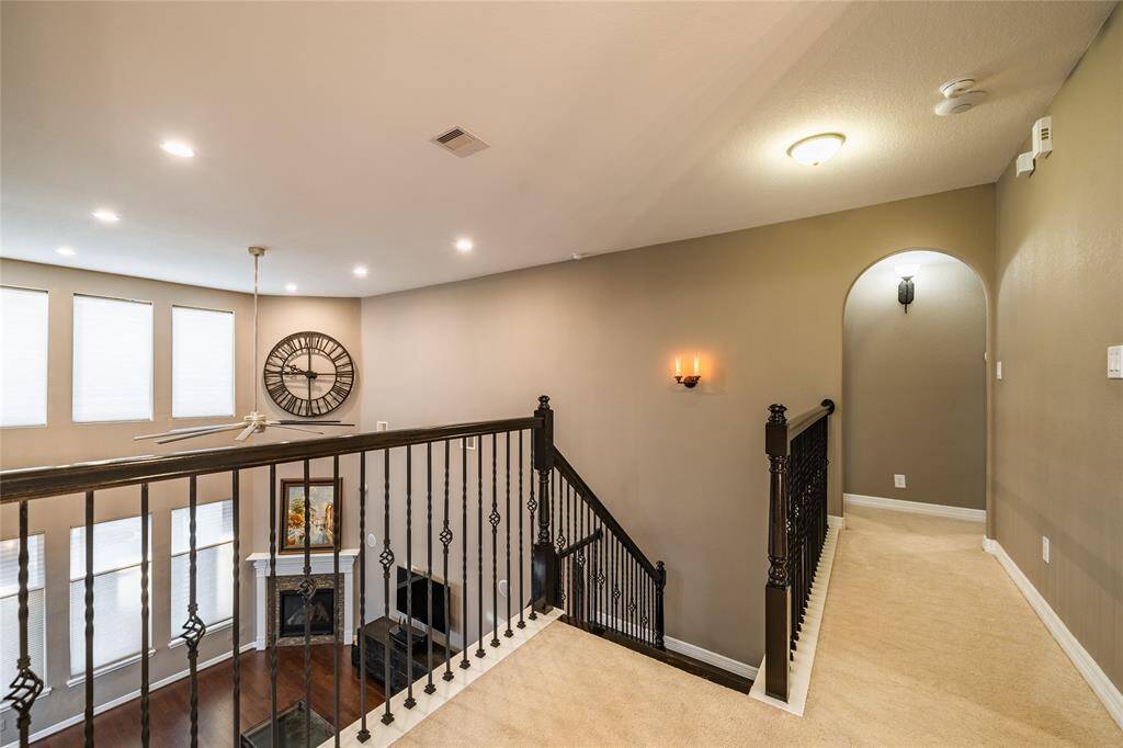 This well-designed stair path leads to the downstairs family space and additional rooms, offering a seamless connection to the home's layout. The elegant wrought iron railing adds a sophisticated touch, while the arched entryway enhances the architectural charm. Overlooking the open living area below, this space provides a sense of openness and natural light, creating an inviting transition to the upper level.