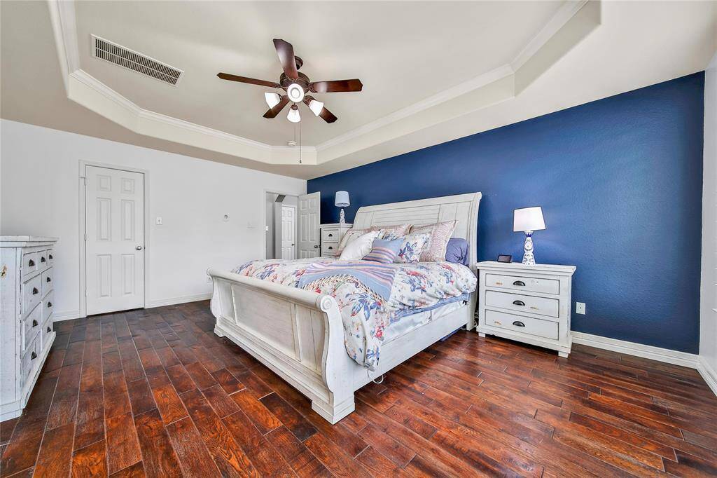 Primary bedroom over looks backyard, highlighted by a tray ceiling with fan for added comfort.
