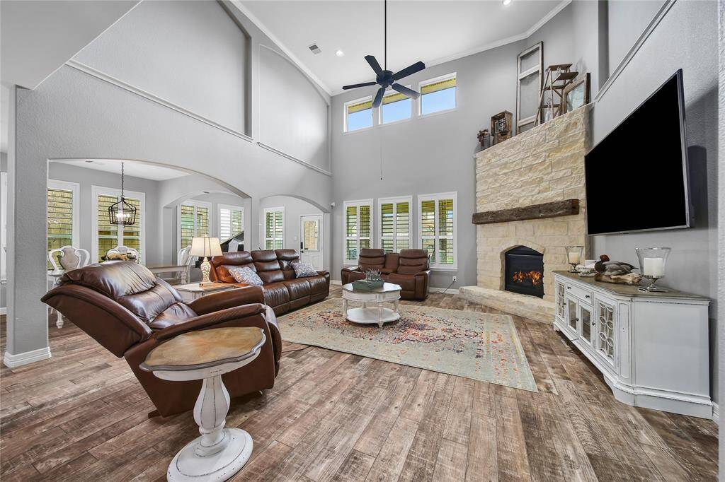 This grand family room is surrounded by plantation shutters, natural light and wood like tile.