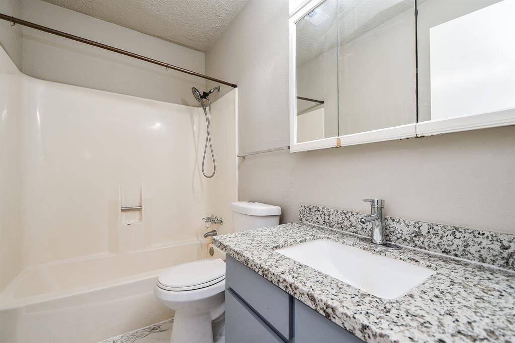 This bathroom features a clean, modern design with a granite countertop, an undermount sink, and a tub-shower combo. The neutral color palette and ample mirror space create a bright, functional space.