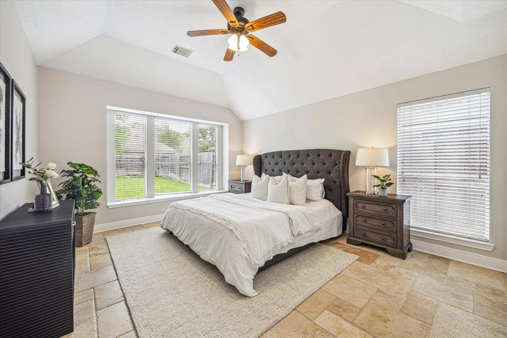 The peaceful primary bedroom has a vaulted ceiling and large windows looking out to the backyard.