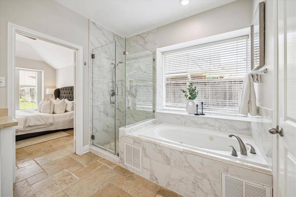 A deep soaking tub invites relaxation, ideally positioned to enjoy natural light and serene views. Adjacent to the tub, a sleek glass shower.
