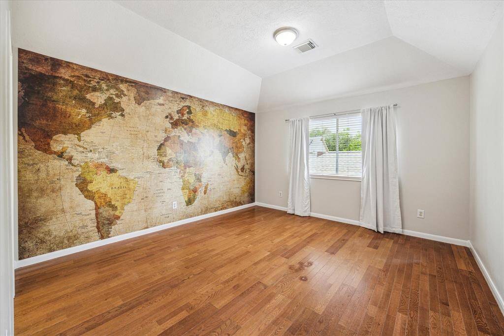 On the other side of the Hollywood bath, this spacious bedroom also has hardwood flooring. A map mural is in place to plan your travels.