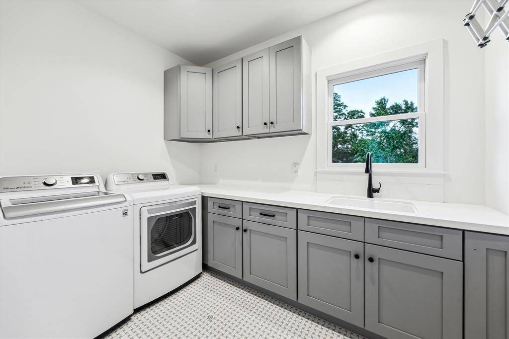Large laundry room with storage, a long countertop perfect for folding, a sink, a built-in hanging rack and stylish basket weave tile floor.
