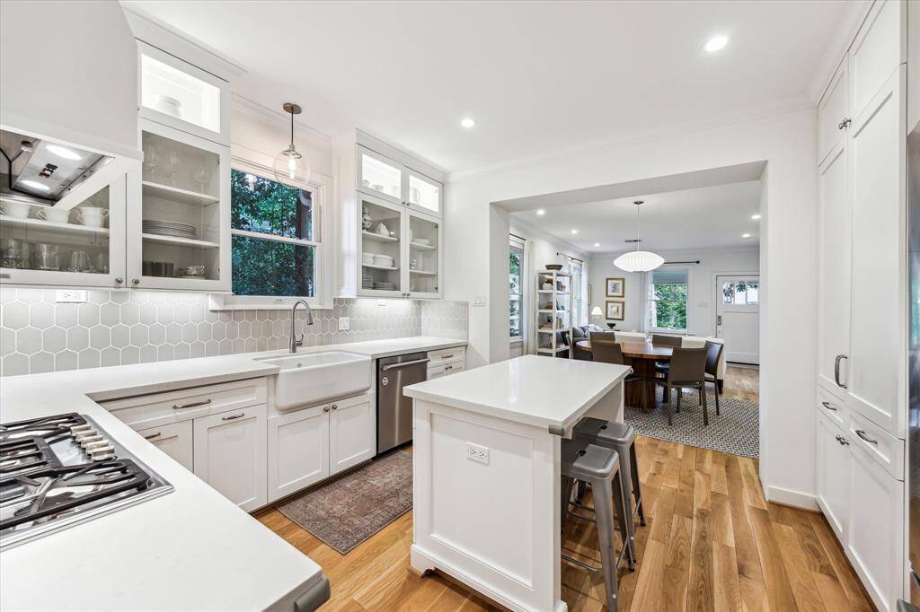 The kitchen was remodeled in 2014 and features quartz counters, a stylish backsplash, custom floor to ceiling cabinetry, paneled vent hood, an apron front sink, breakfast bar, under counter lights and glass front cabinets to showcase your favorite pieces.